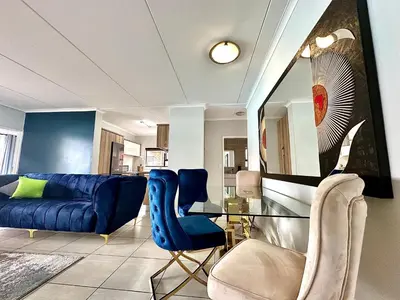a living room with a blue couch and a glass table at The Blyde - 3 Bedroom Lagoon Facing Luxury Apartment in Pretoria