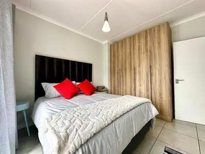 a bedroom with a large bed with red pillows at The Blyde - 3 Bedroom Lagoon Facing Luxury Apartment in Pretoria