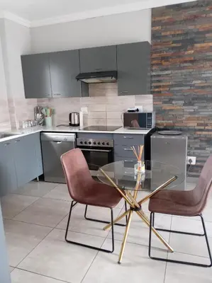 a kitchen with a glass table and two chairs at One-Bedroom Escape in Midrand