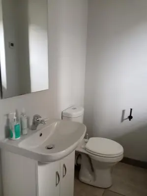 a white bathroom with a toilet and a sink at One-Bedroom Escape in Midrand