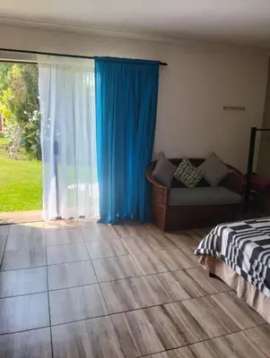 a bedroom with a couch and a blue curtain at Bredell Motel in Bredell