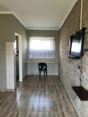 a dining room with a black chair and a window at Bredell Motel in Bredell