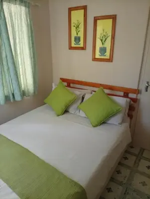 a bedroom with a bed with two green pillows at Manoutsa Holiday Resort in Hoedspruit