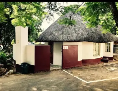 a small house with a thatched roof and a parking lot at Manoutsa Holiday Resort in Hoedspruit
