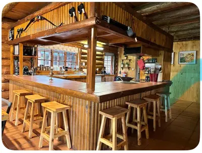 a kitchen with a wooden bar with stools at Little Lions in Dullstroom