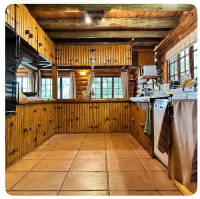 a large kitchen with wooden walls and a tile floor at Little Lions in Dullstroom