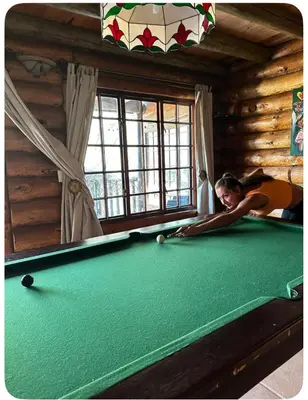 a young woman playing pool in a log cabin at Little Lions in Dullstroom