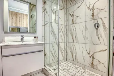 a bathroom with a shower with a sink and a mirror at The Oud at Ellipse Waterfall in Vosburg