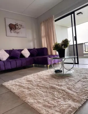 a living room with a purple couch and a rug at The solace in Midrand