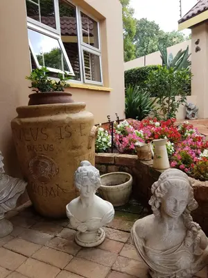two statues of children sitting on the ground in front of a house at Sekelbos Guesthouse in Pretoria