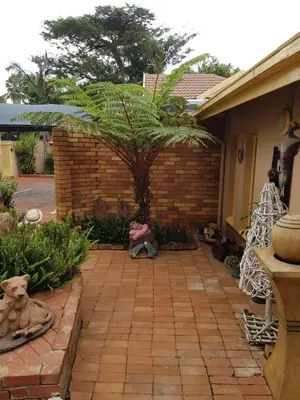 a patio with a palm tree and a brick wall at Sekelbos Guesthouse in Pretoria