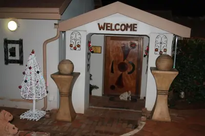 a toy house with a welcome sign and a christmas tree at Sekelbos Guesthouse in Pretoria