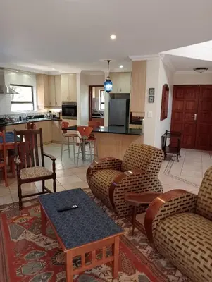 a living room with couches and chairs and a kitchen at Bekkersheim in Pretoria