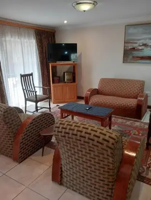 a living room with a couch and chairs and a tv at Bekkersheim in Pretoria