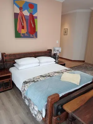 a bedroom with a bed with a painting on the wall at Bekkersheim in Pretoria