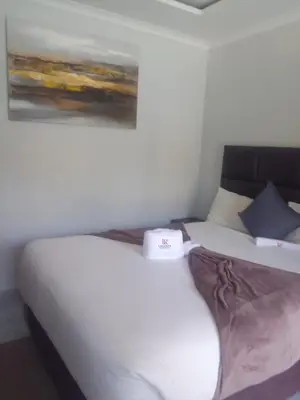 a bedroom with a white bed with a painting on the wall at Laconda Rosa in Kriel