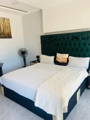 a bedroom with a large bed with a green headboard at Laconda Rosa in Kriel
