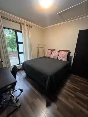 a bedroom with a black bed and a window at The City Escape in Midrand