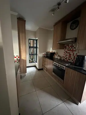 a kitchen with wooden cabinets and a stove top oven at The City Escape in Midrand