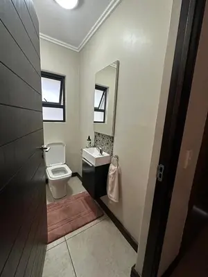a bathroom with a toilet and a sink and a mirror at The City Escape in Midrand