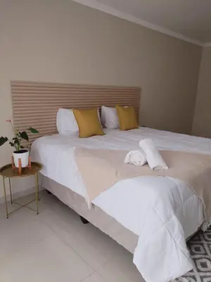 a large bed with white sheets and yellow pillows at 33 On Driedoring in Kempton Park