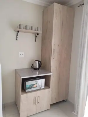 a wooden cabinet with a microwave in a room at 33 On Driedoring in Kempton Park