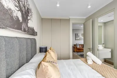 a bedroom with a white bed and a bathroom at RestHaus Suite, Ellipse Waterfall in Midrand