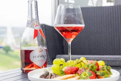 a glass of wine sitting next to a plate of food at RestHaus Suite, Ellipse Waterfall in Midrand
