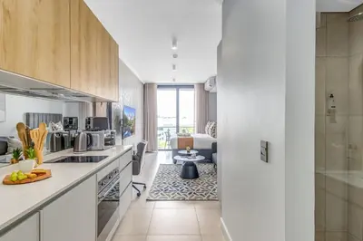 a kitchen with white cabinets and a living room at Serene Spaces, Ellipse in Midrand