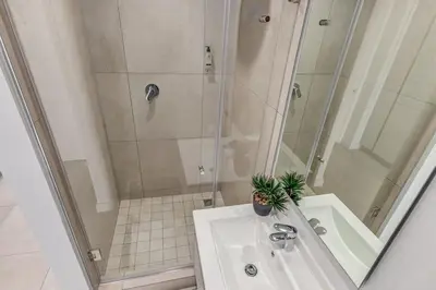 a bathroom with a shower and a sink with a plant at Serene Spaces, Ellipse in Midrand