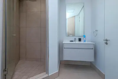 a bathroom with a shower and a sink and a mirror at Ellips Smartz Apartment in Midrand