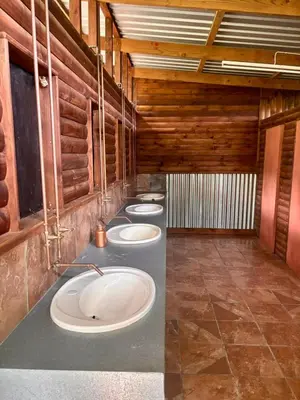 a row of sinks in a bathroom with wooden walls at Camping at Kanaan in Hazyview