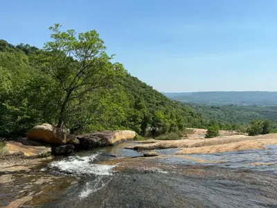 a river on the side of a mountain with trees at Camping at Kanaan in Hazyview