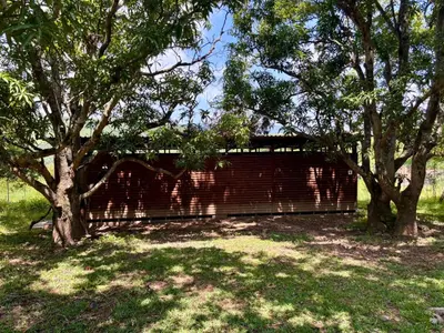 a brick wall in a field with trees at Camping at Kanaan in Hazyview