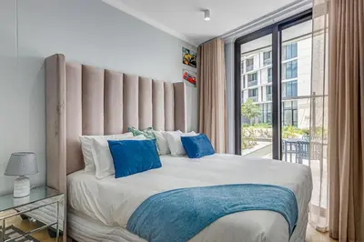 a bedroom with a large bed with blue pillows at The Quanta, Ellipse, Watefall in Midrand