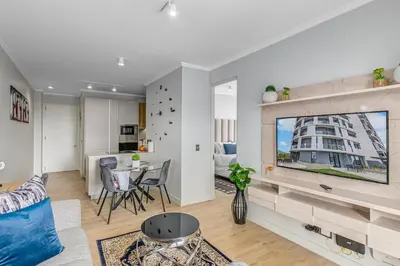 a living room with a couch and a table with chairs at The Quanta, Ellipse, Watefall in Midrand