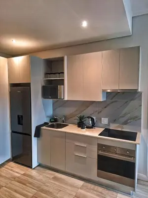 a kitchen with white cabinets and a black refrigerator at Menlyn Maine Apartment - 738 at Maine in Pretoria