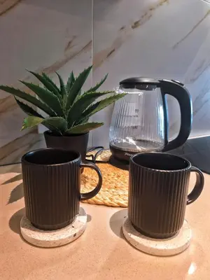 two coffee cups on a table with a potted plant at Menlyn Maine Apartment - 738 at Maine in Pretoria