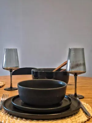 a table with a plate and two wine glasses at Menlyn Maine Apartment - 738 at Maine in Pretoria