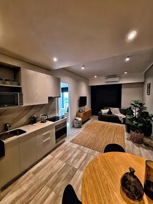 a kitchen and living room with a table and a couch at Menlyn Maine Apartment - 738 at Maine in Pretoria