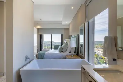 a bathroom with a tub and a bedroom with a bed at #AlimamaSpaces Koki's Place Menlyn in Pretoria