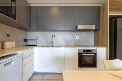 a kitchen with white cabinets and a sink at #AlimamaSpaces Koki's Place Menlyn in Pretoria