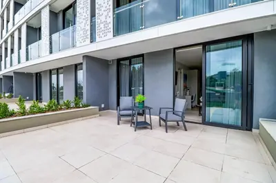 a patio with chairs and a table in front of a building at Waterfall Ellipse-4014 Patimo Opulent Apartment in Midrand