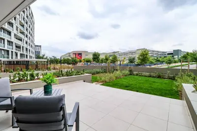 a patio with a table and chairs and a garden at Waterfall Ellipse-4014 Patimo Opulent Apartment in Midrand