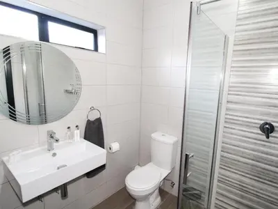 a bathroom with a toilet and a sink and a mirror at De Stroom Studio Apartments in Secunda