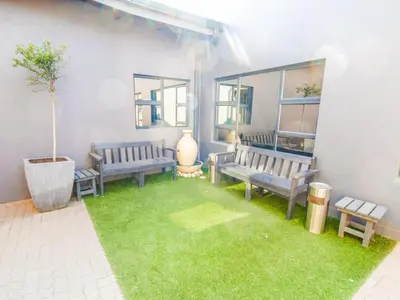 a patio with benches and a green lawn at De Stroom Studio Apartments in Secunda