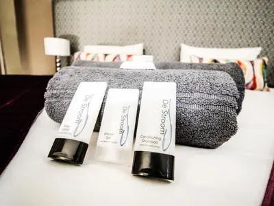 two tubes ofodorizers sitting on a table next to a bed at De Stroom Studio Apartments in Secunda