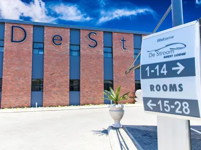 a sign in front of a brick building at De Stroom Studio Apartments in Secunda
