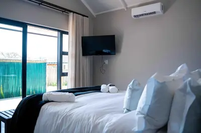 a bedroom with a white bed with a tv on the wall at Atimangeni Bush Guest House in Dwarsloop