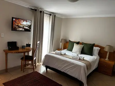 a bedroom with a bed and a table with a desk at Olivestay at Olympus - Studio Apartment in Pretoria